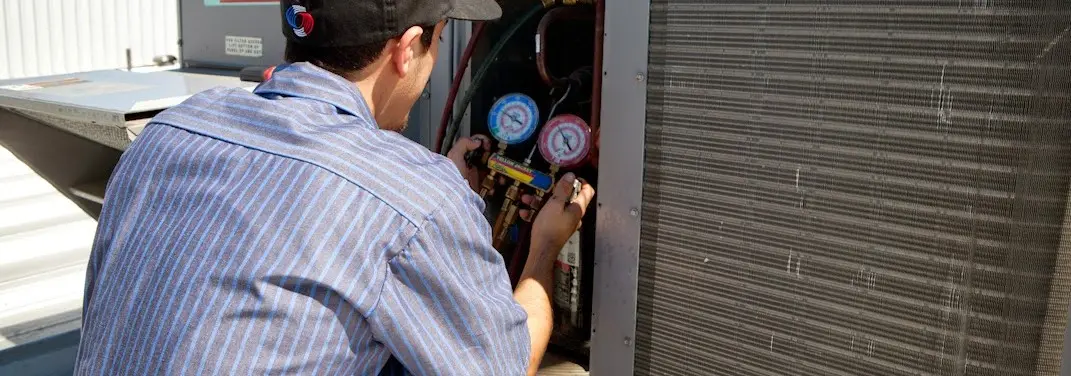 HVAC technician servicing a condenser unit in Northport